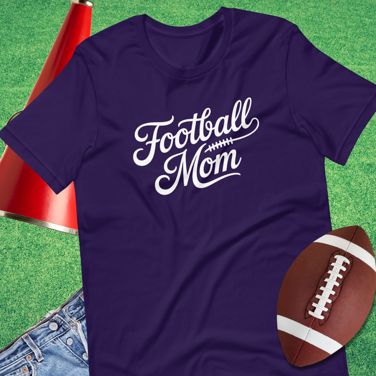 Purple t-shirt with 'Football Mom' text on a grass background with a football and jeans.